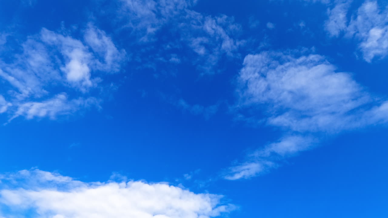 Altocumulus clouds float slowly in the blue sky. Beautiful low angle view on the summer sky with light clouds. Timelapse.