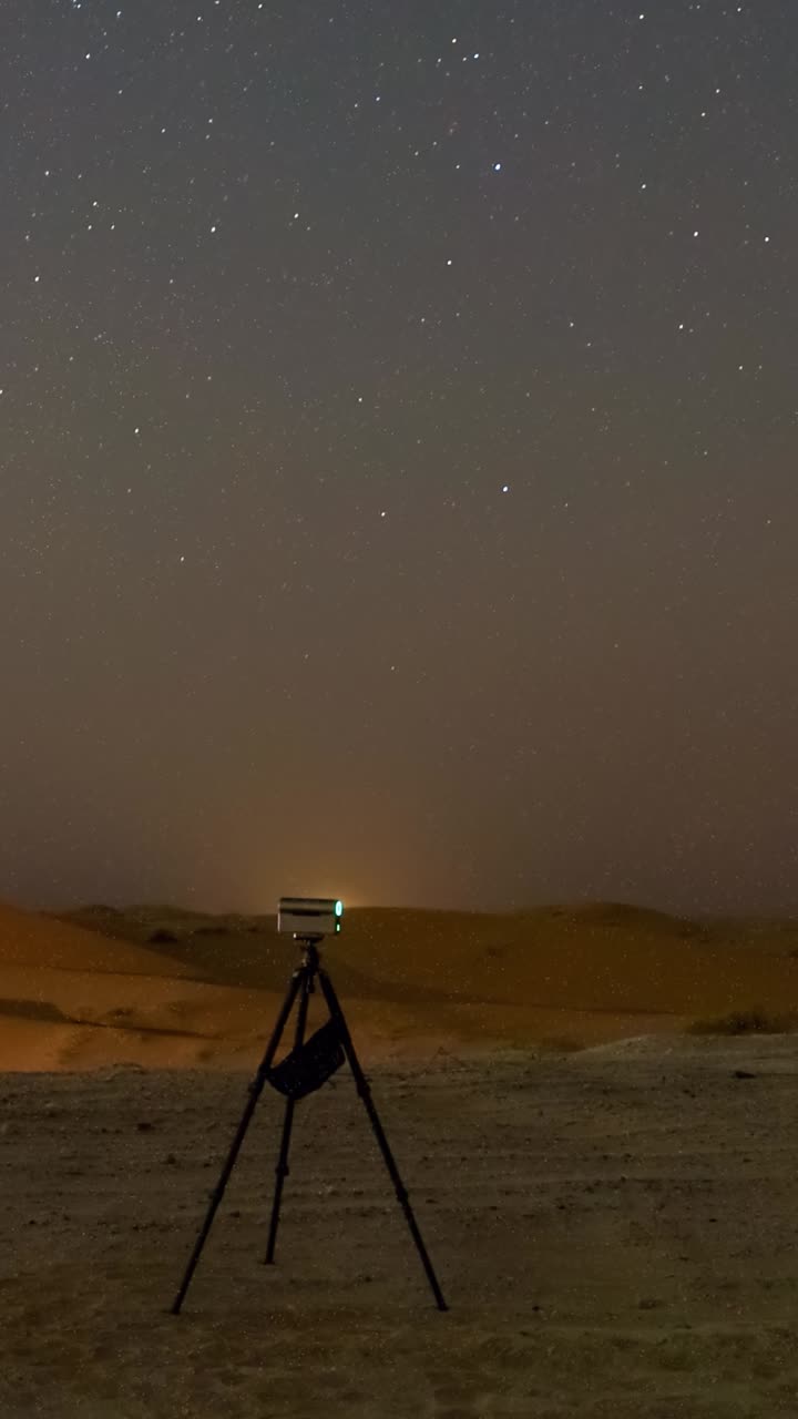 A star gazing party in the Al Qua'a Desert of Abu Dhabi landscape under a starlit sky, with people observing the rising Milky Way core with a smart telescopes - vertical time lapse