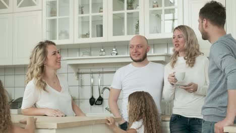 happy women communicate in kitchen with men, children have fun running