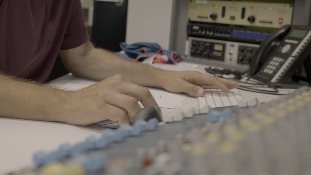 anonymer audiotechniker, der maus und tastatur verwendet, um audio mit software zu mischen, mixer im blick