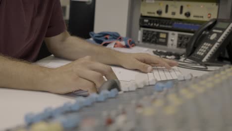 ingeniero de audio anónimo usando mouse y teclado para mezclar audio con software, mezclador a la vista