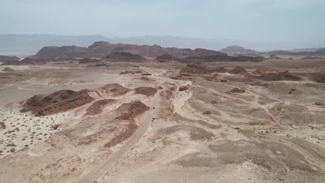 Aerial-view-over-a-car-on-a-desert-road-in-the-Timna,-Israel---tilt,-drone-shot