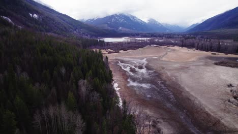 Over-Pine-Tree-Forest,-Dry-Lakebed,-with-Snowy-Mountains-View-during-the-Afternoon-at-St