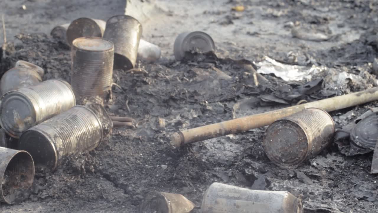 Aluminium tin cans discarded on the ground after a fire
