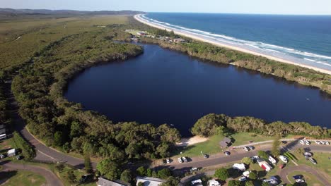 lake ainsworth - freshwater tea tree lake with dark tannins - lennox head, nsw, australia. aerial pullback shot