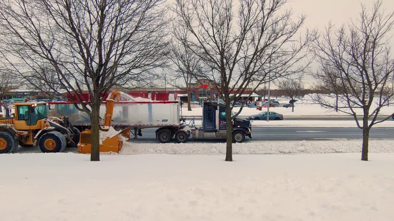 Snow-Go machine and truck work in combination to clear city highway as vehicles go past