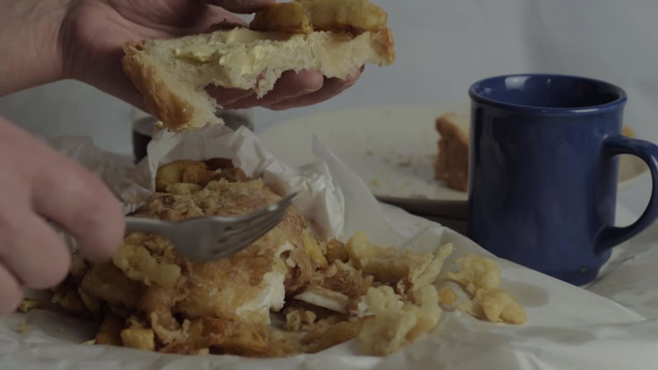 Hand eating fish and chip sandwich close up shot