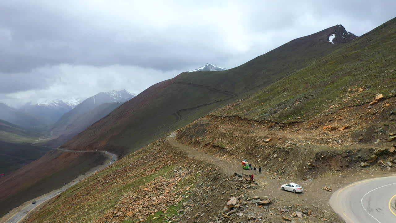 снимок с беспилотника тук-тука, припаркованного на перевале бабусар в пакистане, с несколькими автомобилями на дороге внизу в долине каган, широкий обзорный снимок