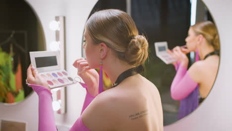 female dancer using make up next to her colleagues