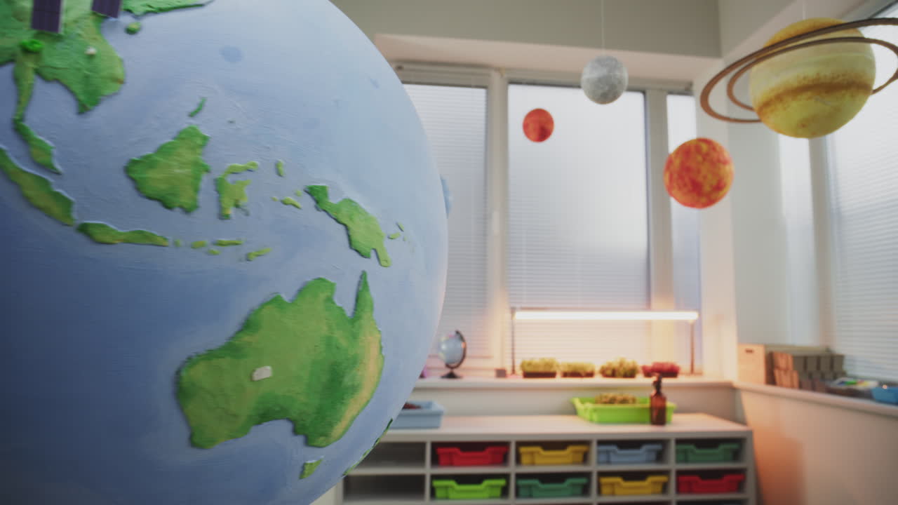 Close Up of Globe with Miniature 3D Models of Wind Turbines and Solar Panels in Modern Classroom