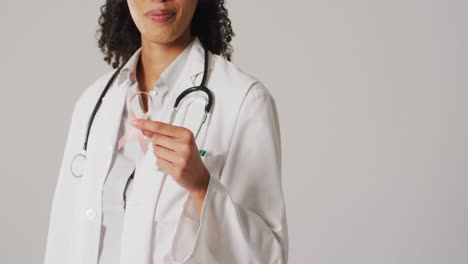 Video-of-smiling-biracial-female-doctor-holding-pink-breast-cancer-ribbon