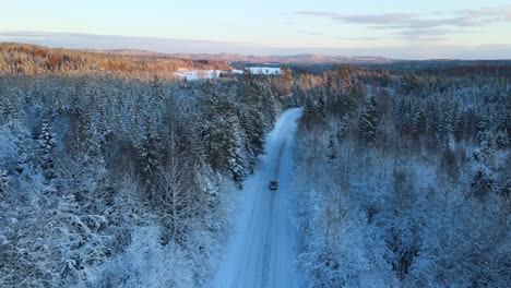 Car-driving-down-a-snow-covered-road-in-the-forest-during-winter