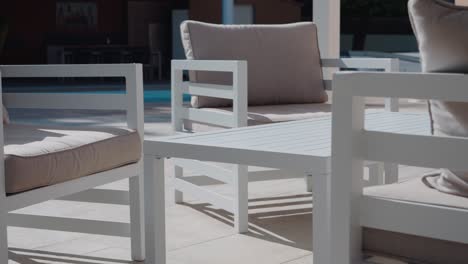 slow orbiting shot of garden patio furniture with a swimming pool behind