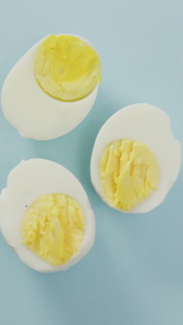 video of overhead view of three egg halves on blue background