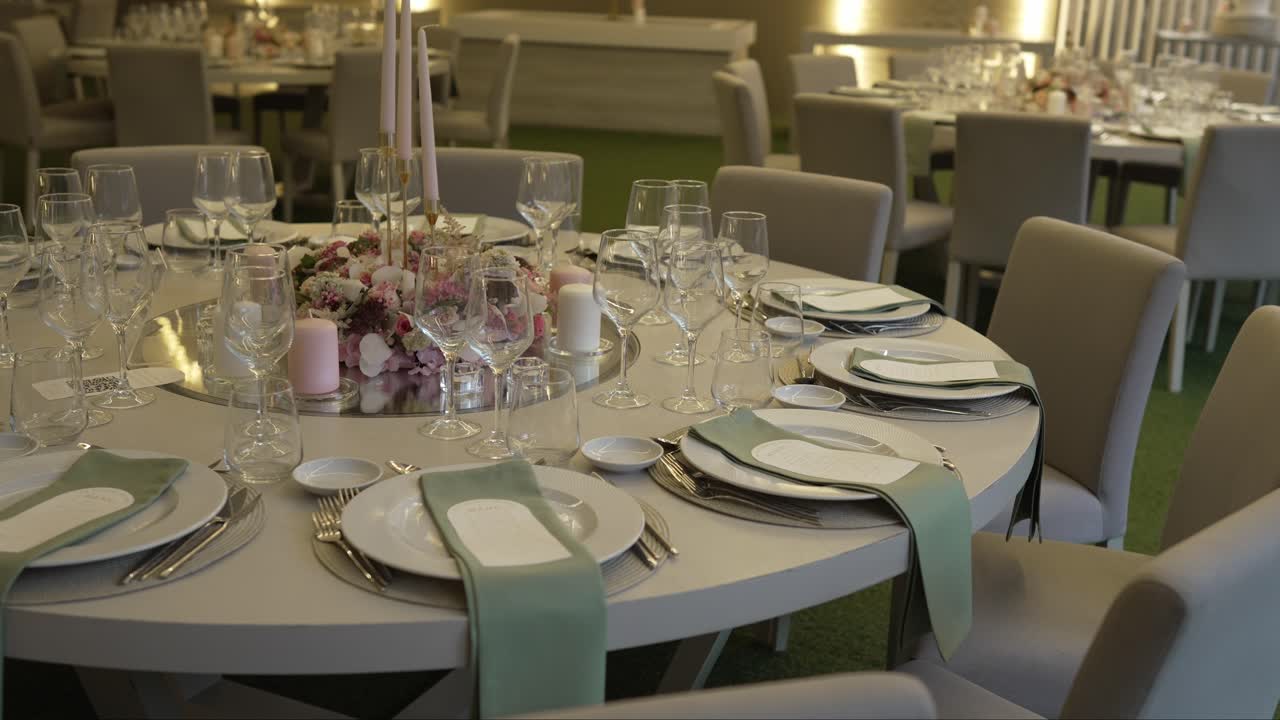 round table set with glassware napkins and soft pink floral centerpiece for wedding dinner