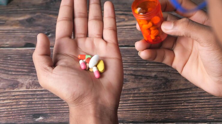 Person pouring pills from a container onto their hand