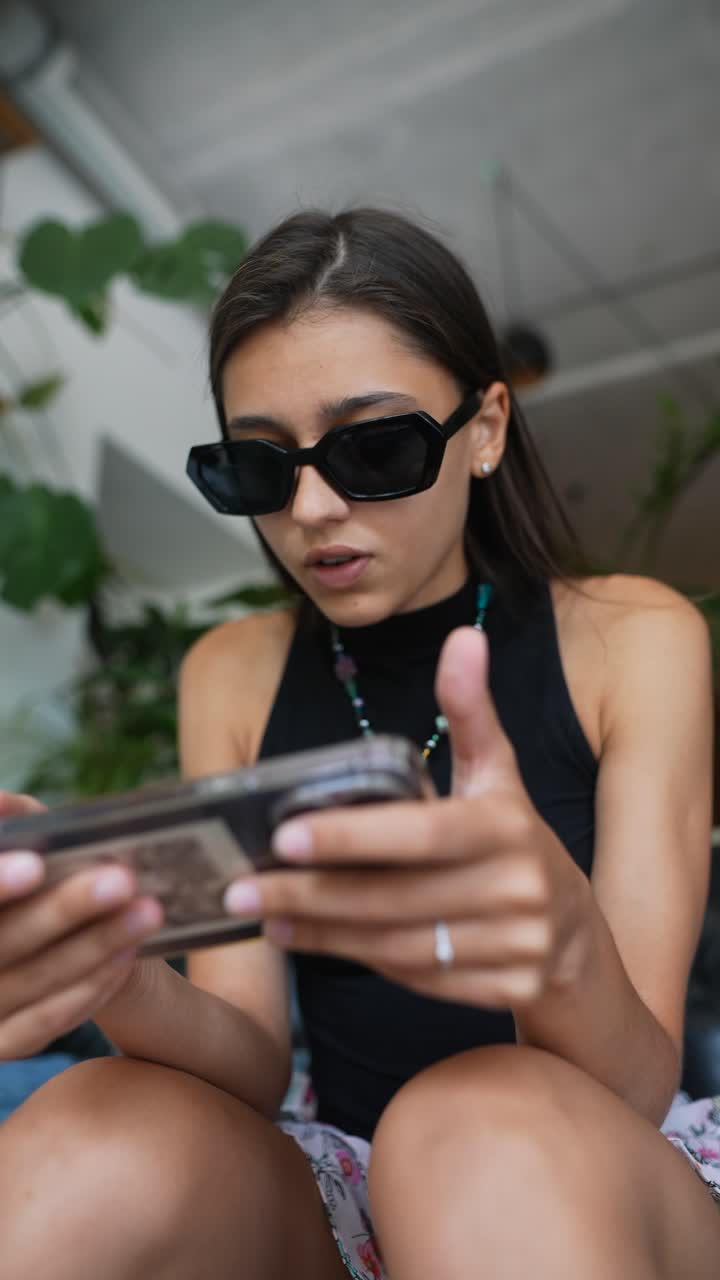 una mujer joven jugando a juegos en un teléfono inteligente en un café