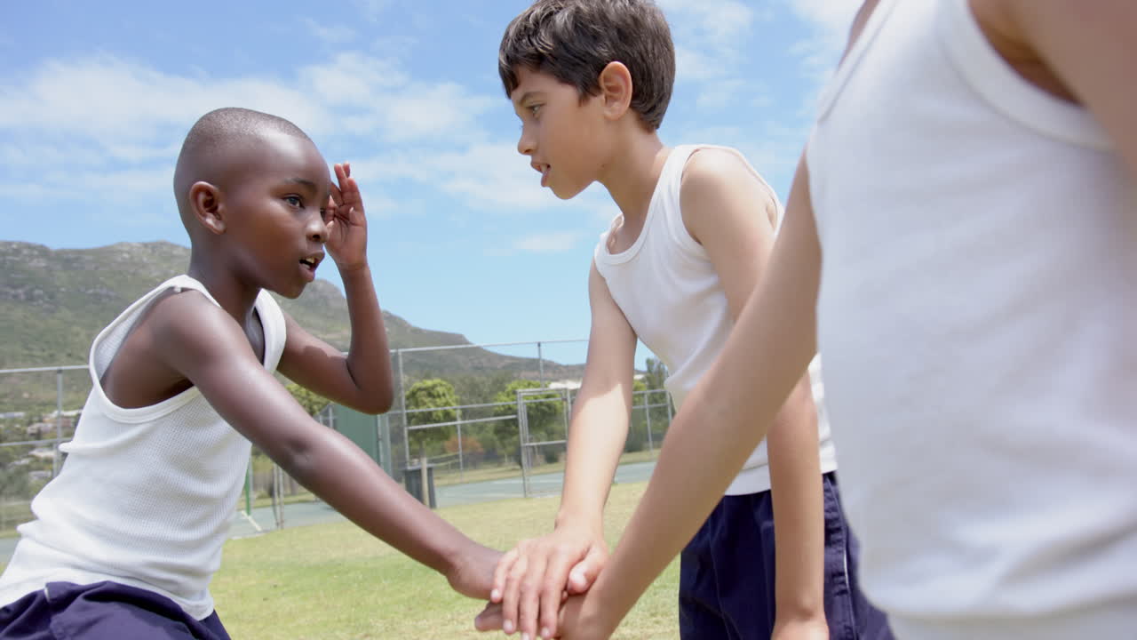 In school, group of children putting hands together in teamwork outdoors