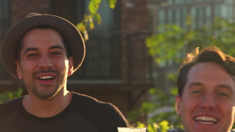 Three-male-friends-gesturing-to-camera-at-a-rooftop-party,-close-up