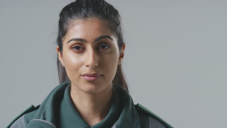 close up studio portrait of serious young female paramedic against plain background