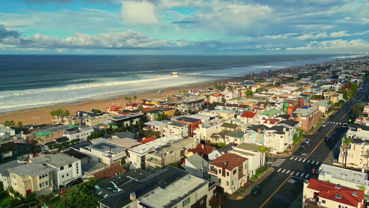 Cảnh quay từ flycam trên không qua Bãi biển Manhattan với Cầu tàu Manhattan Beach nhô ra mặt nước Thái Bình Dương, dọc theo các dãy nhà dân