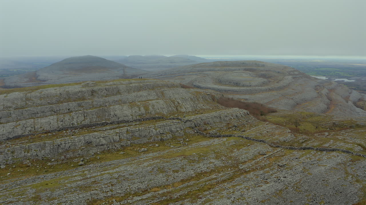 Hikers atop Mullaghmore peak, aerial showcasing stunning views. County Clare.