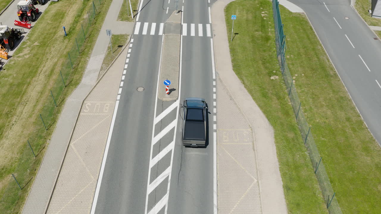 High angle drone shot tracking a EV truck driving on a sunny neighborhood road