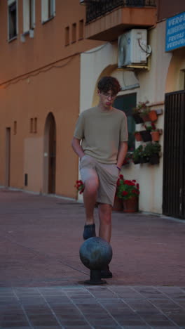 young man's playful interaction with a street bollard at dusk