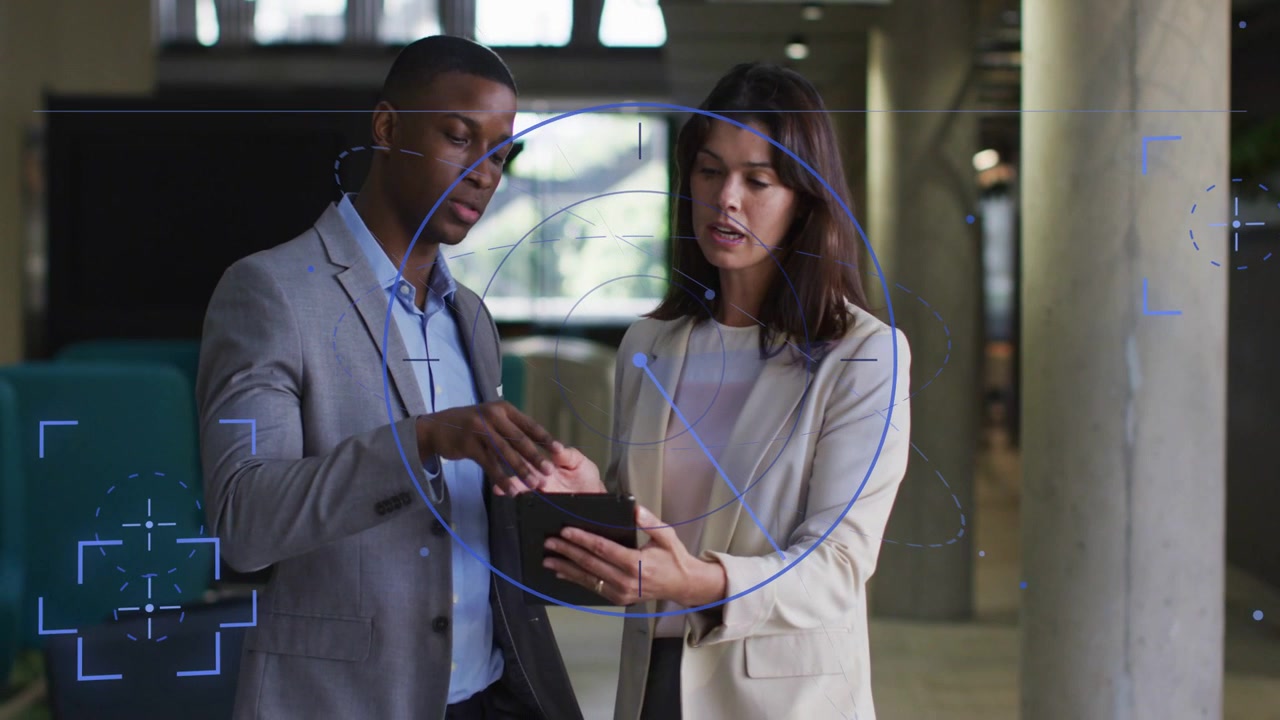 Man tapping tablet, woman holding device, leaning, reviewing charts while blue HUD highlights data