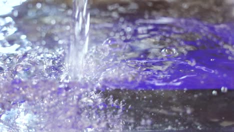 slow motion, water is poured in clear container creating refreshing bubbles and surging underwater