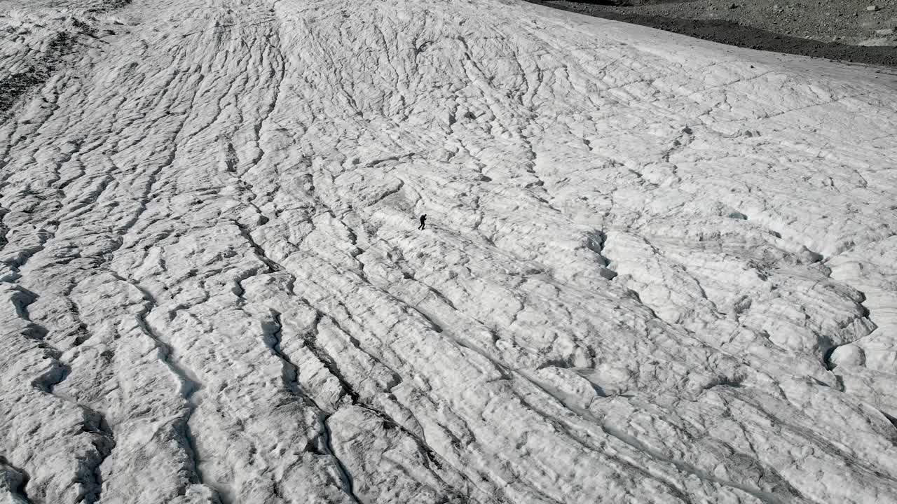 sobrevuelo aéreo alrededor de un excursionista caminando a través del hielo del glaciar allalin cerca de saas-fee en valais, suiza en un día soleado en los alpes suizos