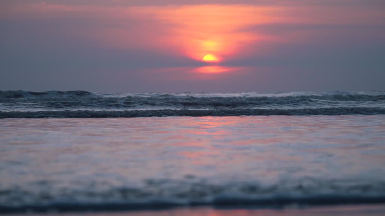 ビーチで地平線に触れるリラックスした波、紫の空、金色の太陽、ビーチでのカラフルなロマンチックな夏の夕日、インドのビーチ