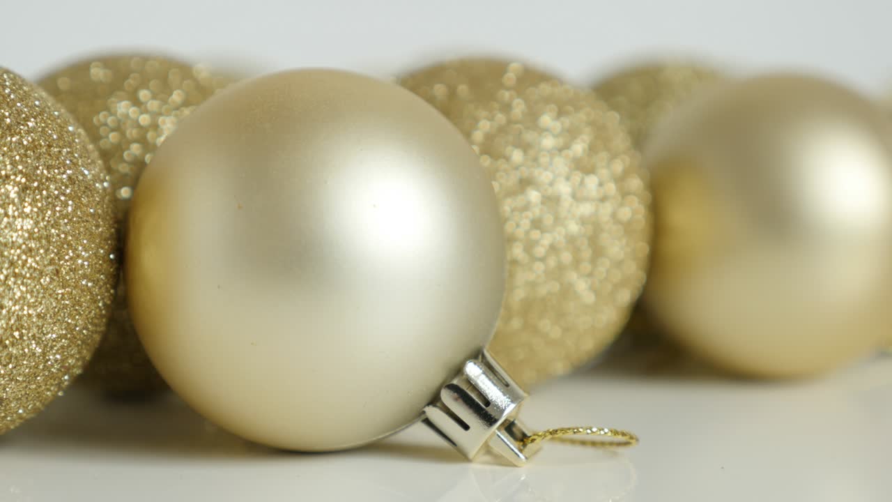 Palline di Natale dorate su sfondo bianco in primo piano, filmato 4K