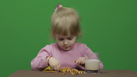 The-child-eats-cookies.-A-little-girl-is-eating-cookies-sitting-on-the-table.