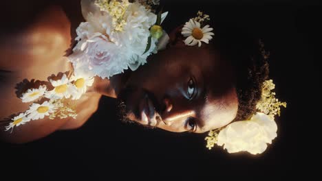 studio portrait of young black man adorned with flowers