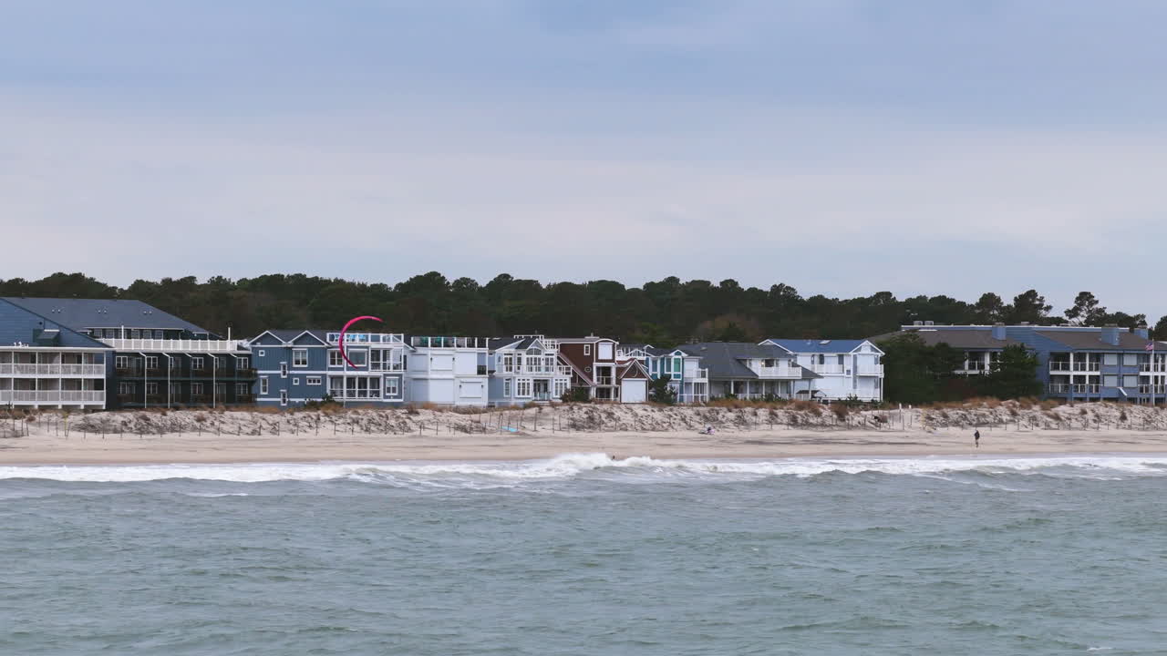 Drone tracking a Kite surfer riding to a beach in Delaware, cloudy day in USA