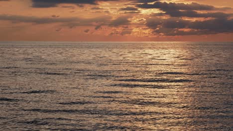 Sunset-over-sea,-ocean-water-with-calm-waves-and-beautiful-light,-steady-shot