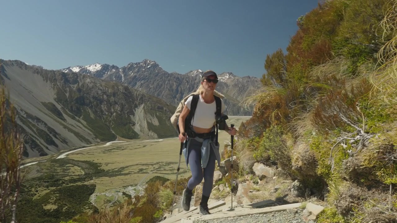 Escursionista bionda atletica che sale il sentiero Sealy Tarns in Nuova Zelanda, scala verso il paradiso.