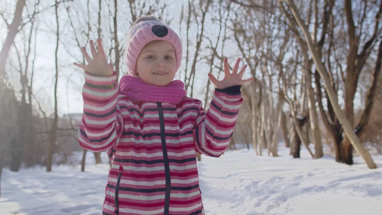 웃는 아이, 웃고 춤을 추는 아이, ok 표지판을 보여주는 아이, 은 겨울 공원의 눈 인 도로에서 엄지손가락을 올리고