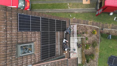 top down view of workers install solar panels on a residential rooftop - solar energy, sun power