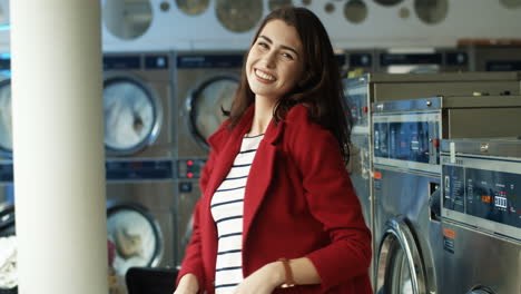 beautiful cheerful woman in stylish outfit having fun and dancing in laundry service room while machines washing on background 1