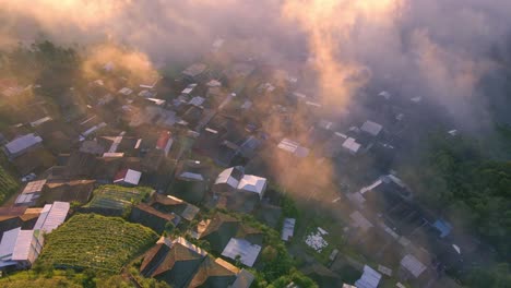 aerial view of village in the highlands shrouded in mist illuminated by the rays of the rising sun