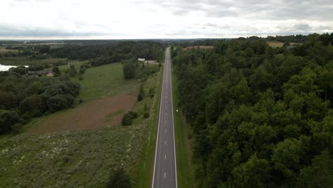 aerial shot of the long highway with driving cars surrounded by green lush trees from both sides-1