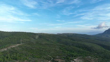 Imágenes-Prores-De-Un-Dron-Volando-Sobre-Las-Verdes-Montañas-De-Trucafort-Con-Un-Parque-Eólico-De-Fondo