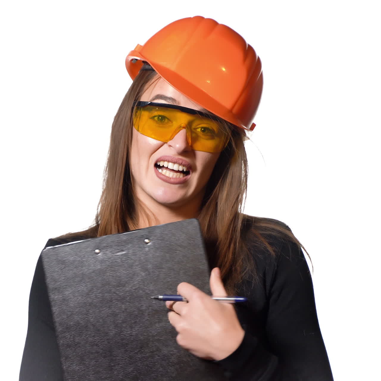 Pretty woman engineer in an orange helmet tells a story about something and holds a folder-tablet with pen in her hands on a white background.