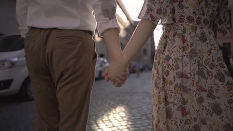 lovers holding hands and walking forward at sunrise in rome