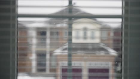 Looking-out-the-window,-slow-motion-snow-fall-in-the-backyard-of-suburban-homes