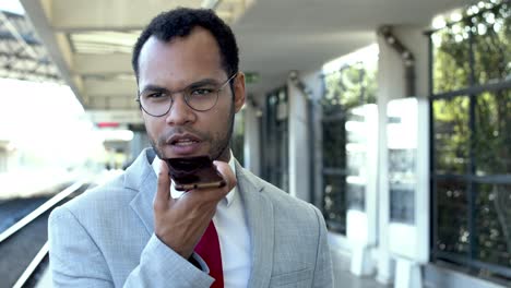 businessman with mobile phone at train station