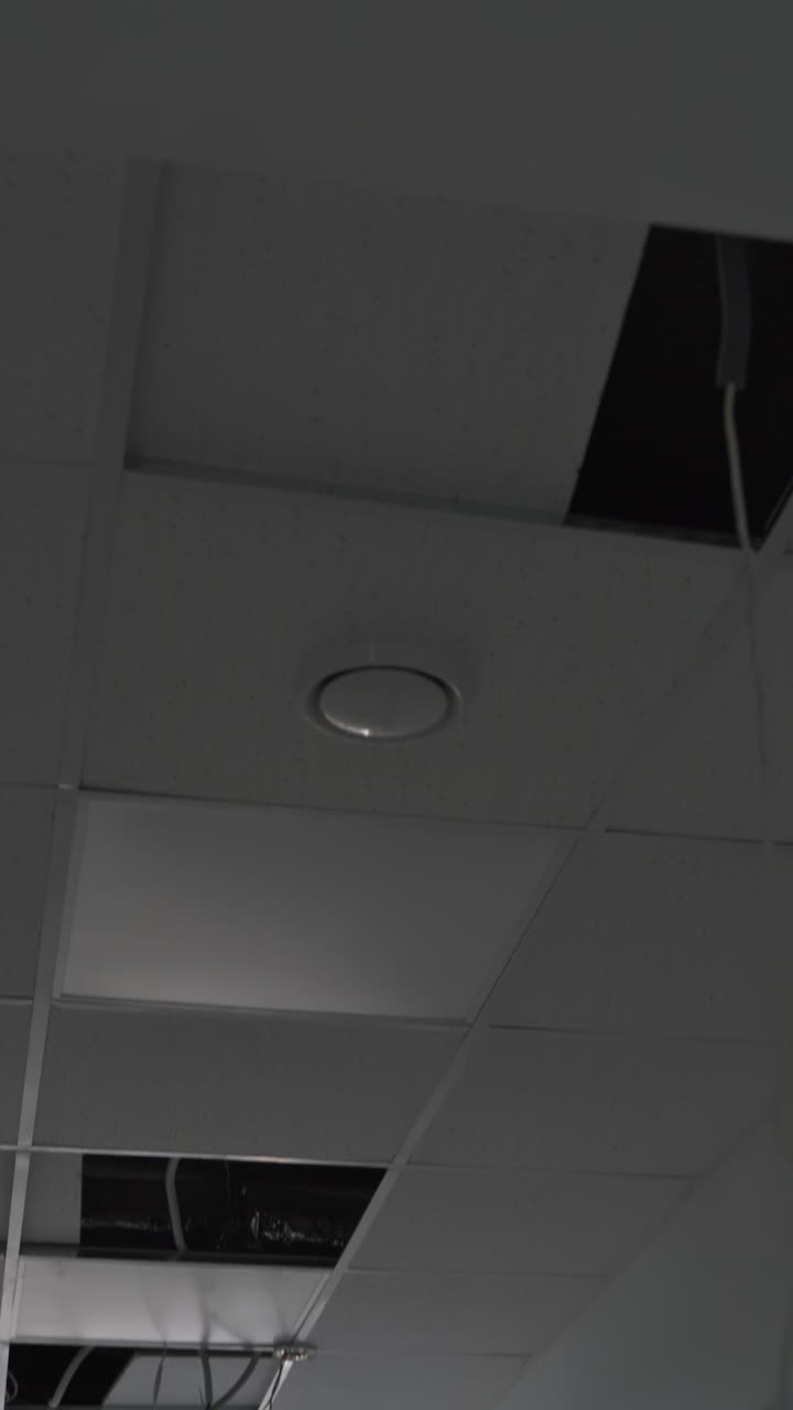 Recently built premises with unfinished inside works. Light system in the process of installation. Wires hanging from the ceiling. Vertical video