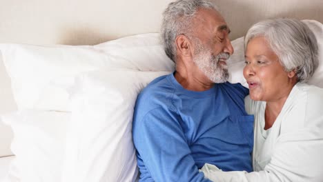 Feliz-Pareja-Birracial-De-Ancianos-Tumbada-En-La-Cama-Y-Abrazándose,-Inalterada,-En-Cámara-Lenta